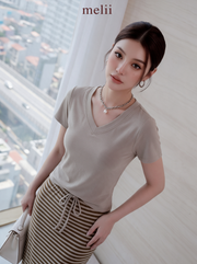 MELII Mira V-Neck Drawstring Top and Striped Maxi Skirt Set in Beige, close-up model view showing the V-neckline and drawstring detail