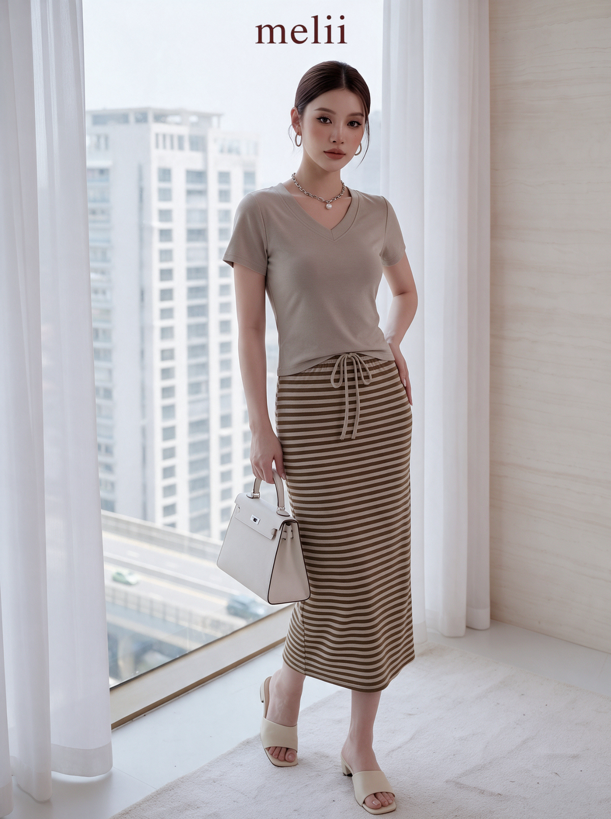MELII Mira V-Neck Drawstring Top and Striped Maxi Skirt Set in Beige, full-length angled model view with a white handbag